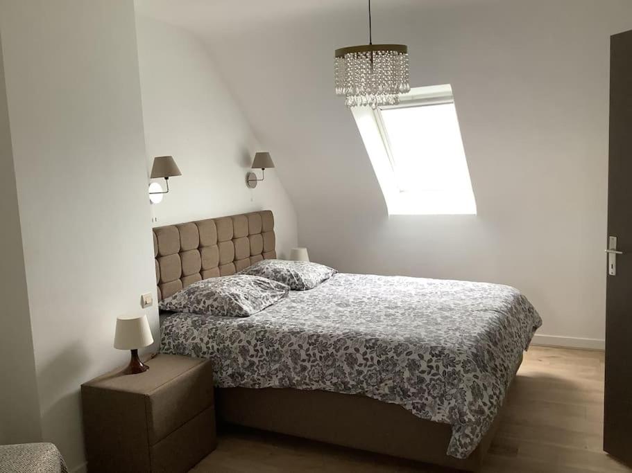 una camera da letto con un letto e un lampadario di Maison Monts d’Arree 3 chambres a Sizun