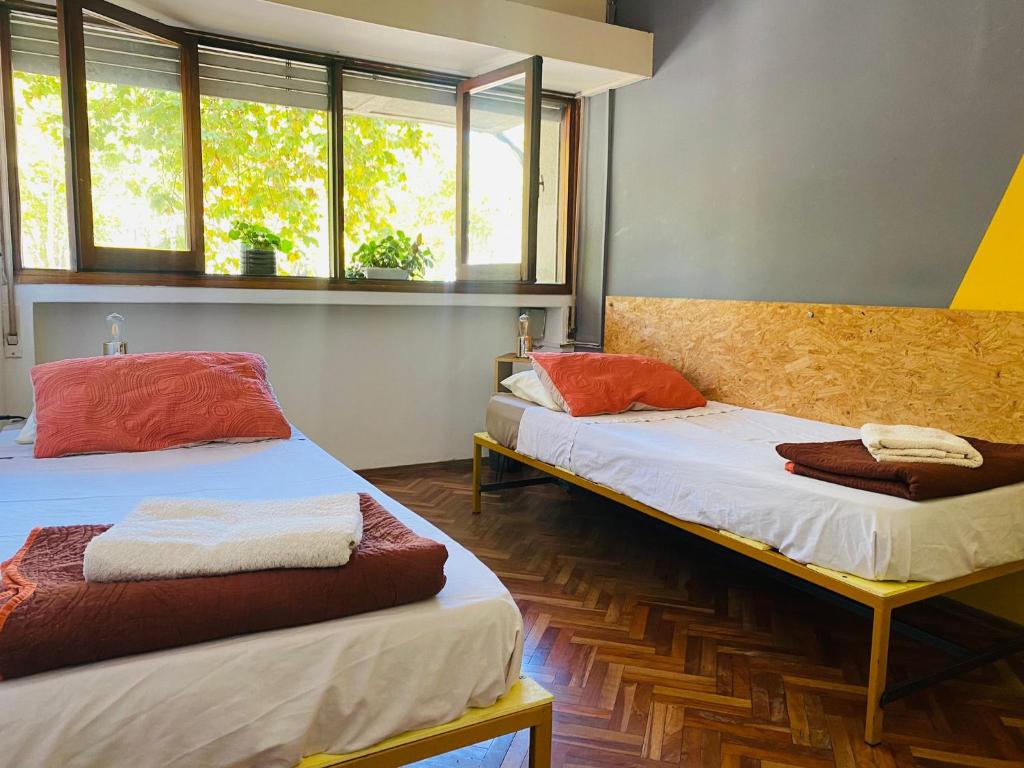 two beds in a room with two windows at Youki Haus Hostel in Montevideo