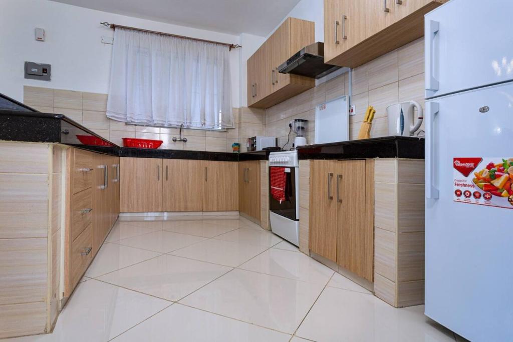 een keuken met houten kasten en een witte koelkast bij Lathembo Serviced Apartments in Nairobi