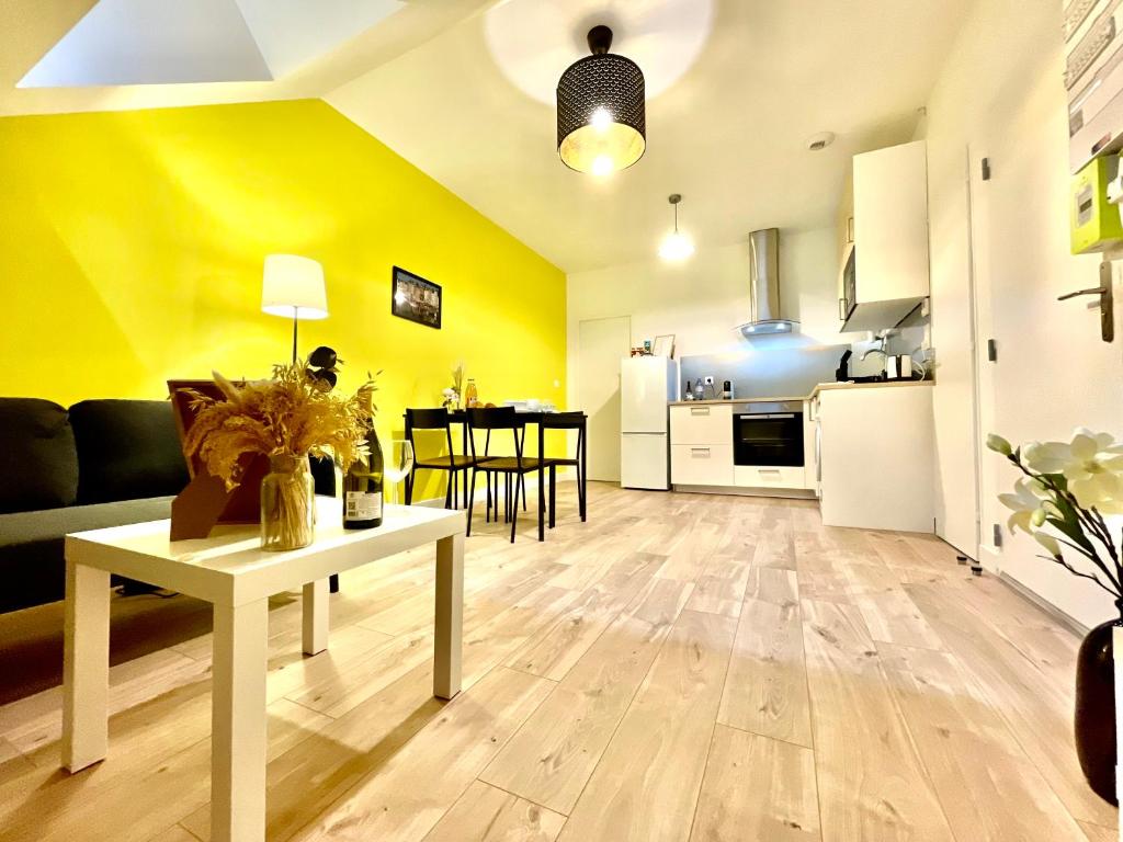 ein Wohnzimmer und eine Küche mit gelben Wänden und einem Tisch in der Unterkunft Le Yellow Peak - Centre Ville - Maison Boucicaut - BY PRIMO C0NCIERGERIE in Chalon-sur-Saône