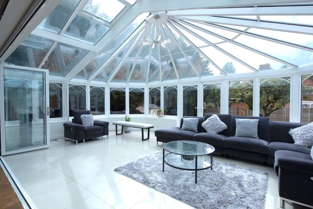 a conservatory with couches and a glass ceiling at Luxury 6 bedroom house with parking - Northwood in Northwood