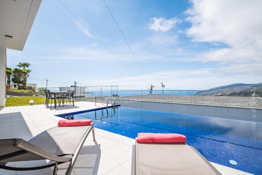 uma piscina com vista para o oceano a partir de uma casa em Villa Camelia em Arco da Calheta