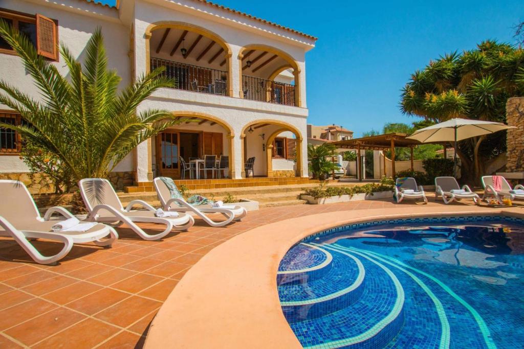 a villa with a swimming pool in front of a house at Villa Oceanic - PlusHolidays in Calpe