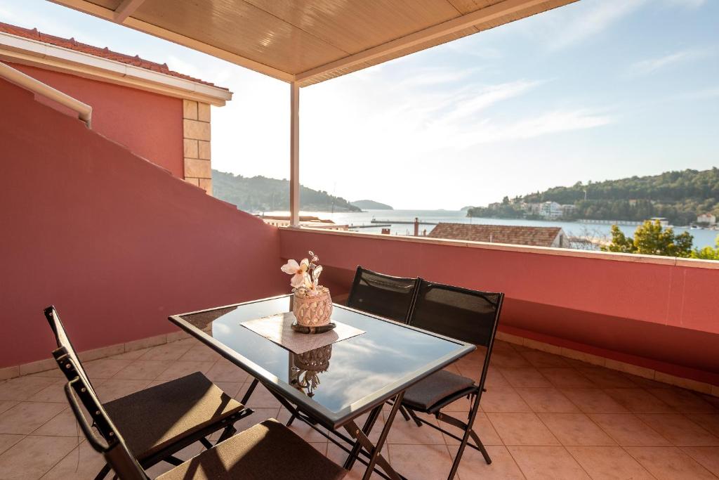 einen Tisch und Stühle auf einem Balkon mit Blick auf das Wasser in der Unterkunft Michael's House in Vela Luka