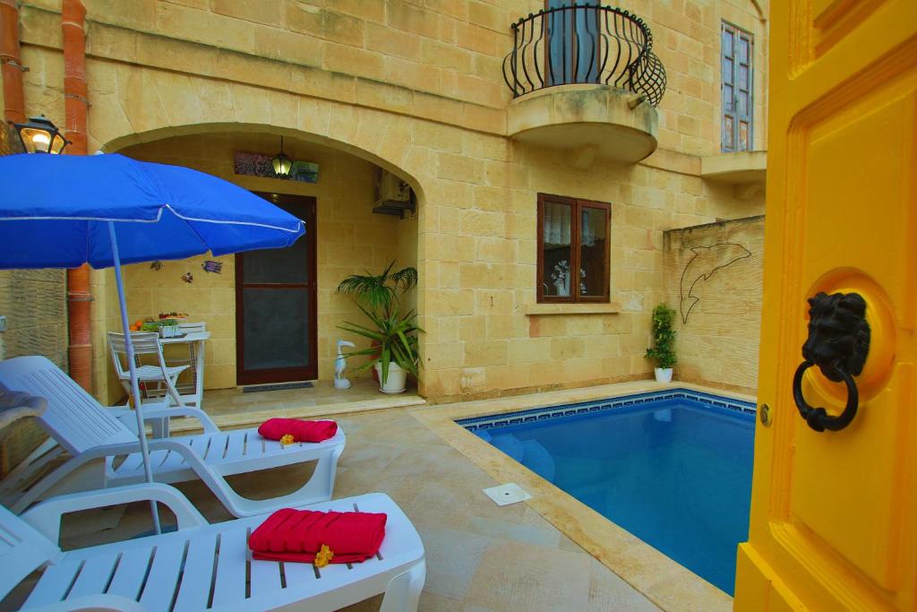 a swimming pool with two chairs and an umbrella at Farmhouse Renee in Qala