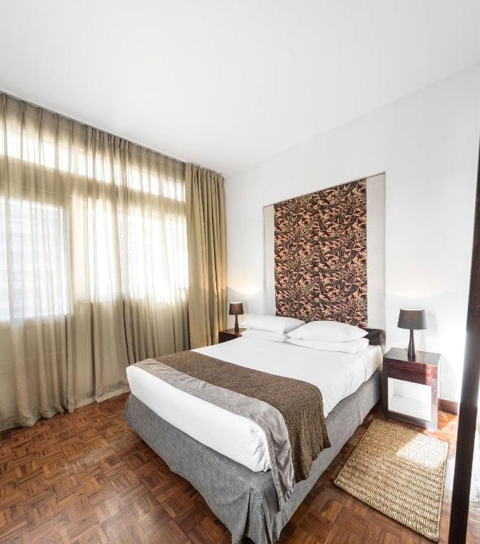 a bedroom with a large bed and a large window at Hotel Tivoli Beira in Beira