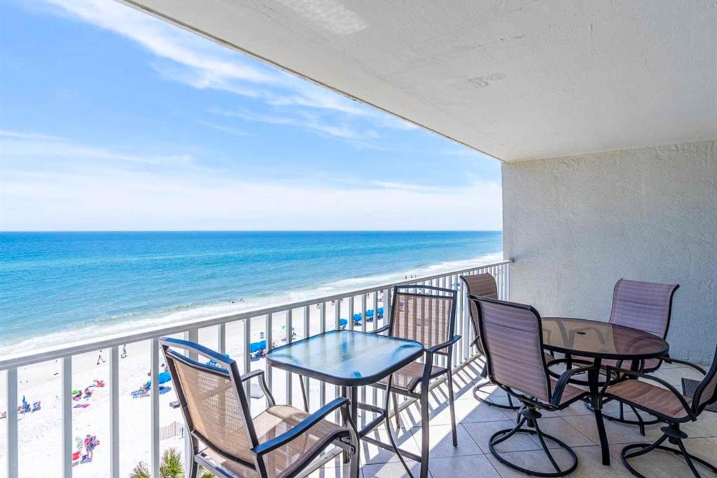a balcony with chairs and tables and the ocean at Ocean House II 2602 in Gulf Shores