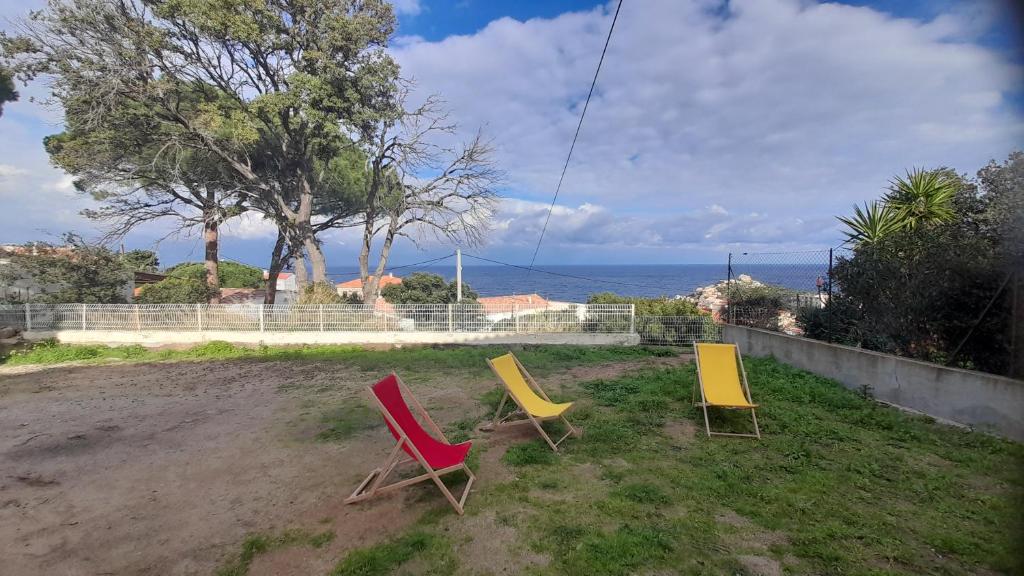 tres sillas sentadas en un patio con el océano en el fondo en Calvi, T3, vue mer, grande terrasse en Calvi