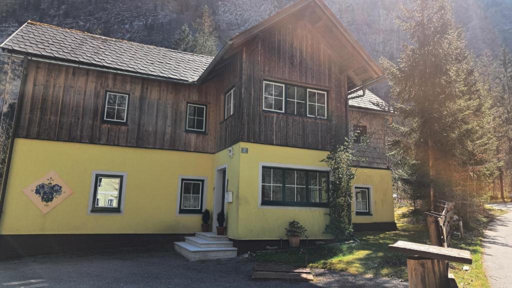 a house with a wooden roof and a yellow at Haus Waldbach in Hallstatt