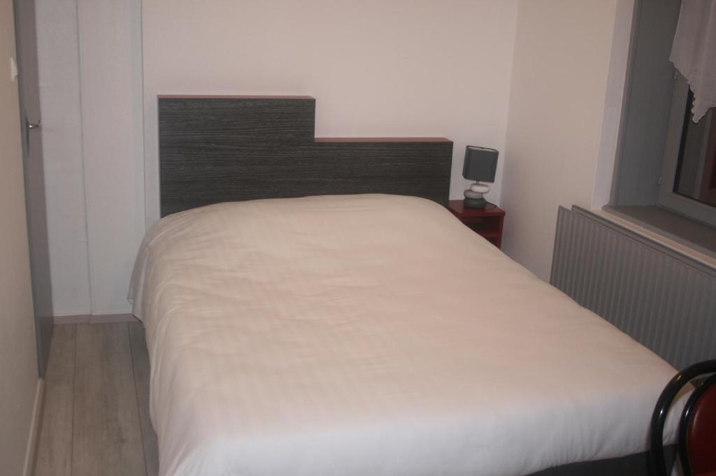 Schlafzimmer mit einem weißen Bett mit einem Kopfteil aus Holz in der Unterkunft Le P'tit Bouchon in Rambervillers