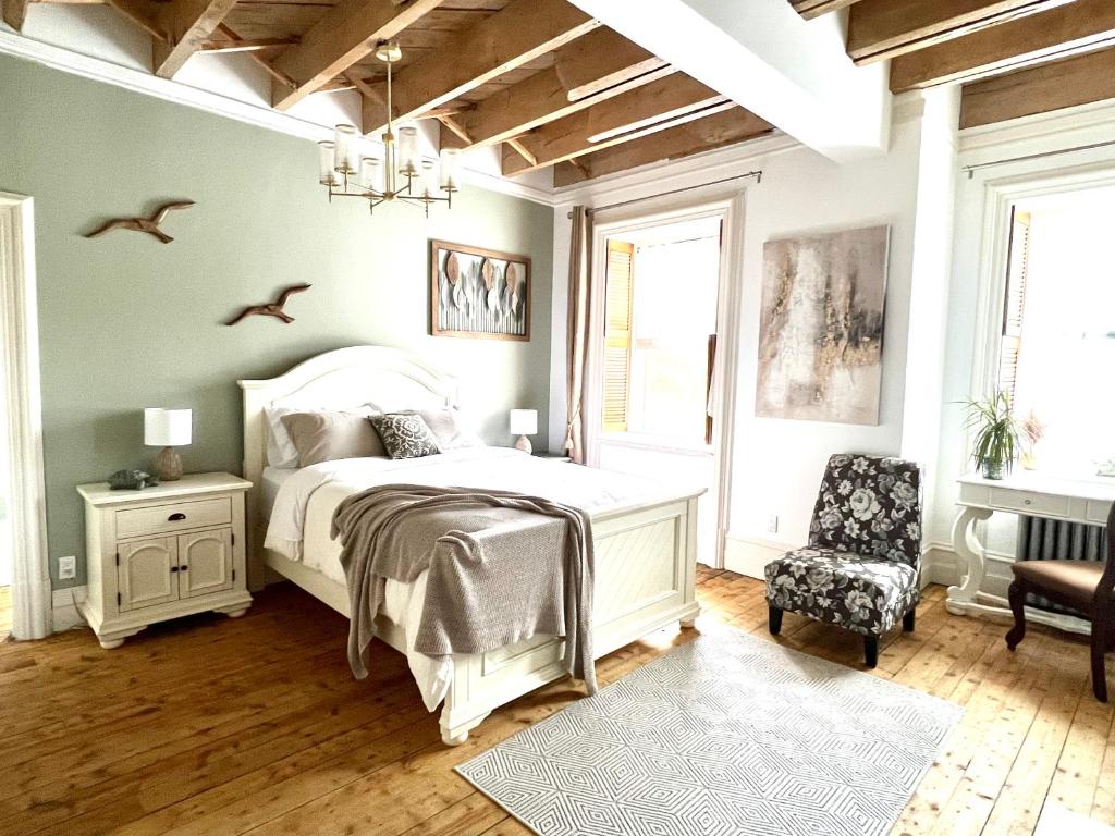 a bedroom with a white bed and a chair at La Demeure du Capitaine in Neuville