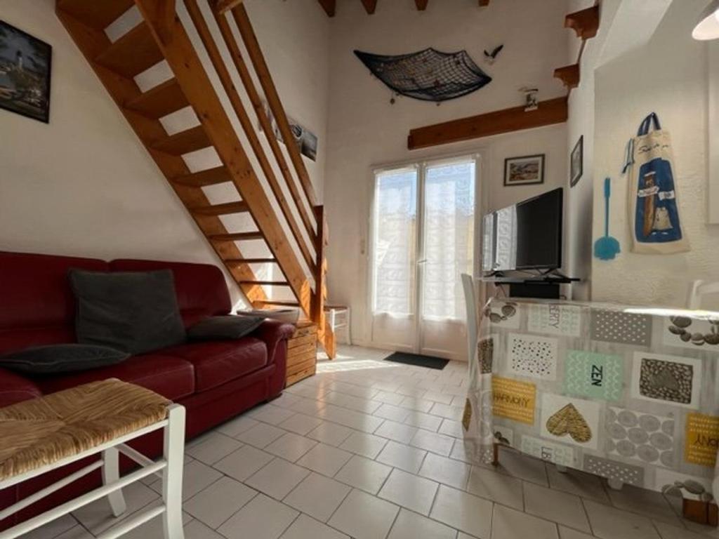 salon z czerwoną kanapą i telewizorem w obiekcie Charmante maison 3 pièces, 2 pas plage et forêt, 4 couchages, WIFI, stationnement, ménage inclus - St Georges d'Oléron - FR-1-246A-152 w mieście Saint-Georges-dʼOléron
