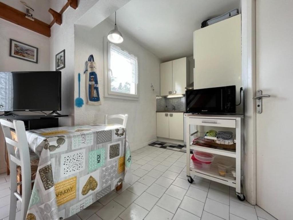 kuchnia ze stołem i kuchenką mikrofalową w obiekcie Charmante maison 3 pièces, 2 pas plage et forêt, 4 couchages, WIFI, stationnement, ménage inclus - St Georges d'Oléron - FR-1-246A-152 w mieście Saint-Georges-dʼOléron