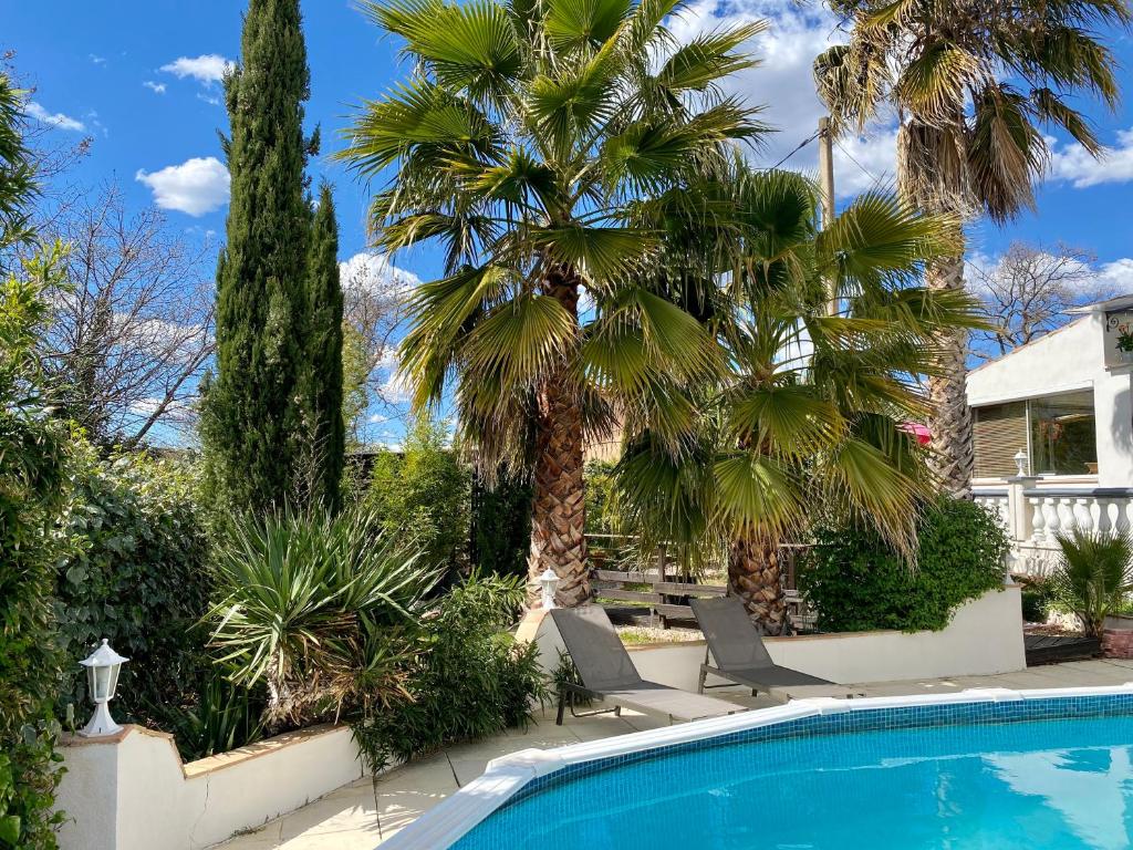 a swimming pool with two chairs and palm trees at Appartement in Flayosc