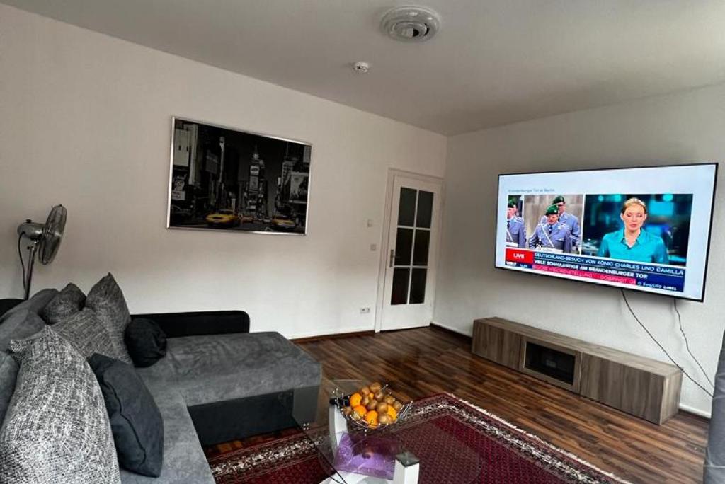 uma sala de estar com um sofá e uma televisão de ecrã plano em Private Rooms em Hanôver