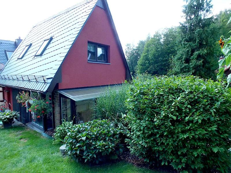 una casa roja con techo de gambrel y algunos arbustos en Ferienhaus Zum Gründel, en Prossen