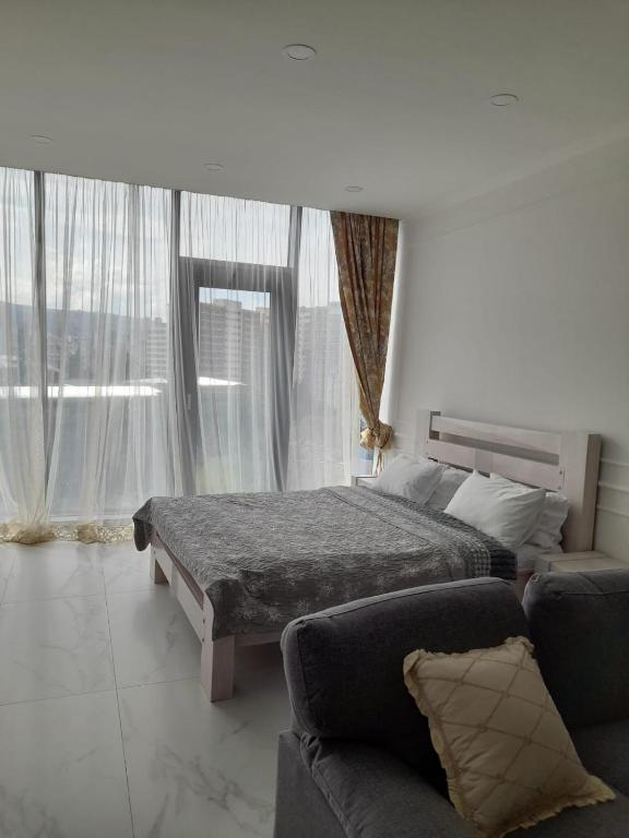 um quarto com uma cama, um sofá e janelas em White King em Tbilisi
