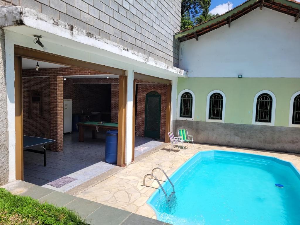 una piscina junto a un edificio con mesa de billar en Chácara dos Sonhos em Mairiporã en Mairiporã