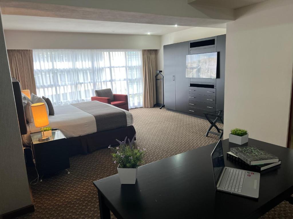 um quarto de hotel com uma cama e uma secretária em St Isidro Suites Corporate Housing SPA & Wellness Center em Cidade do México
