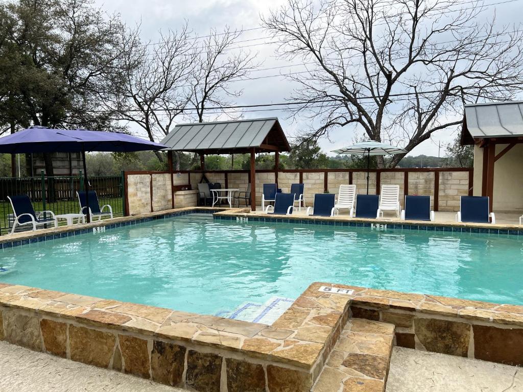 a large swimming pool with blue chairs and umbrellas at Gruene Cottages in New Braunfels