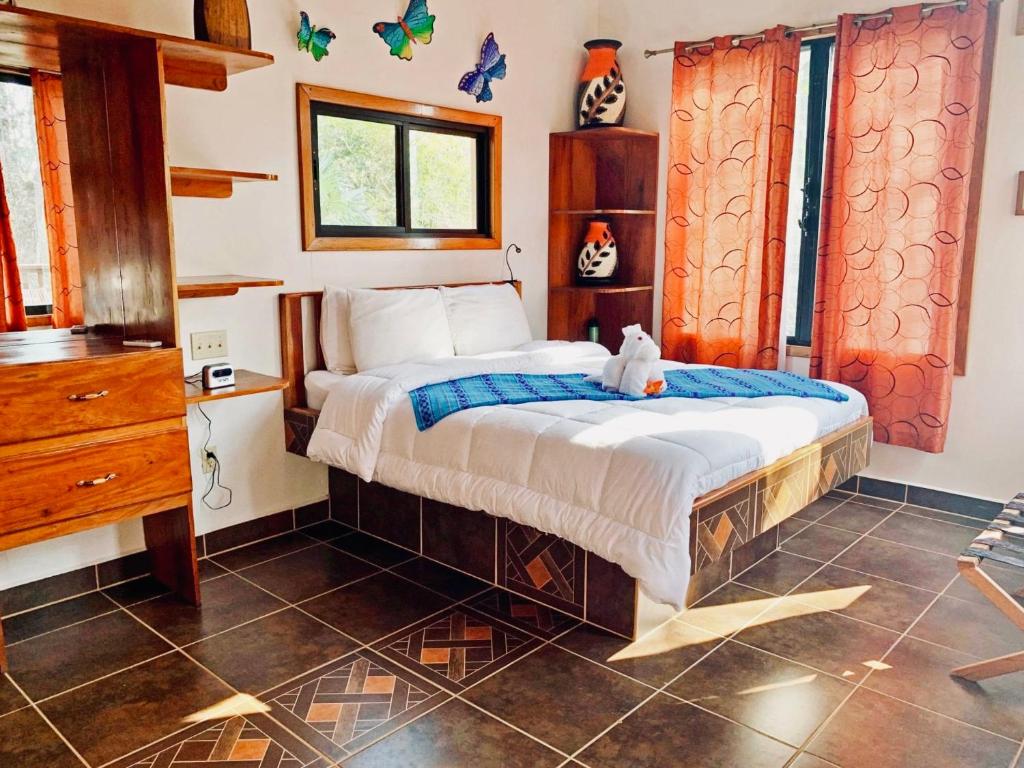 um quarto com uma cama com um urso de peluche sentado sobre ele em Mariposa Jungle Lodge em San Ignacio