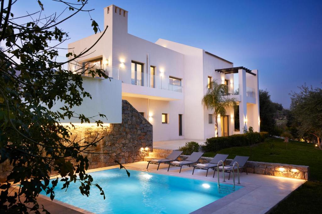 a villa with a swimming pool at night at Arbora Olea Luxury Resort in Skaleta