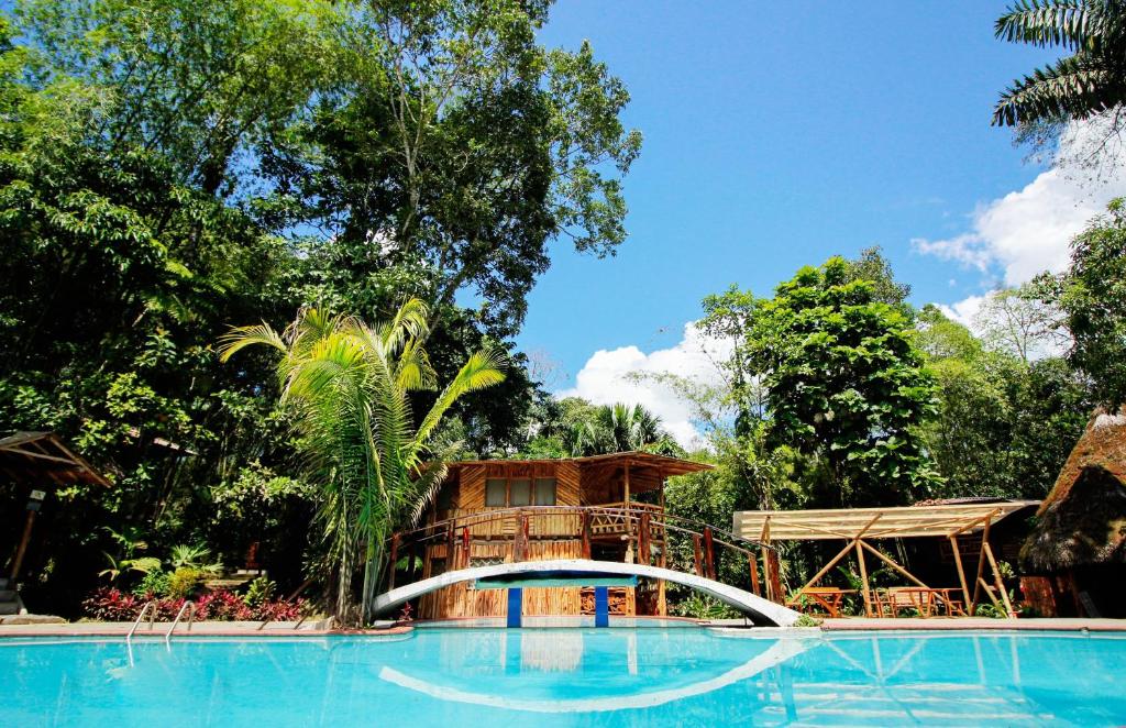 a resort with a large swimming pool with a tree house at Hosteria Flor de Canela in Puyo