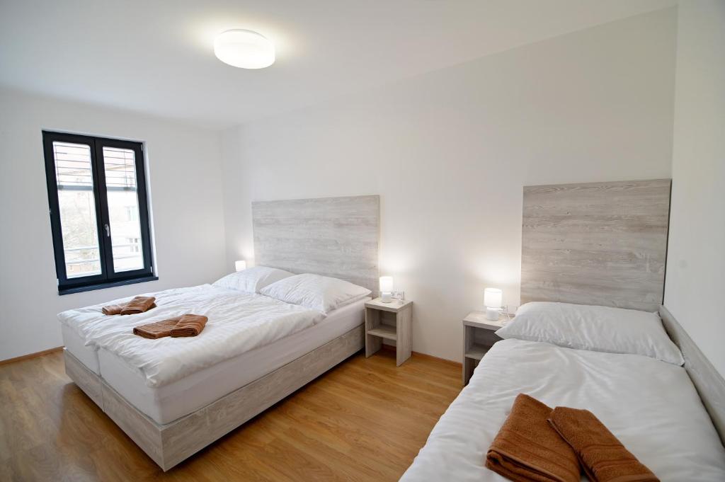two beds in a room with white walls and wooden floors at Penzion U Vinaře in Mikulov