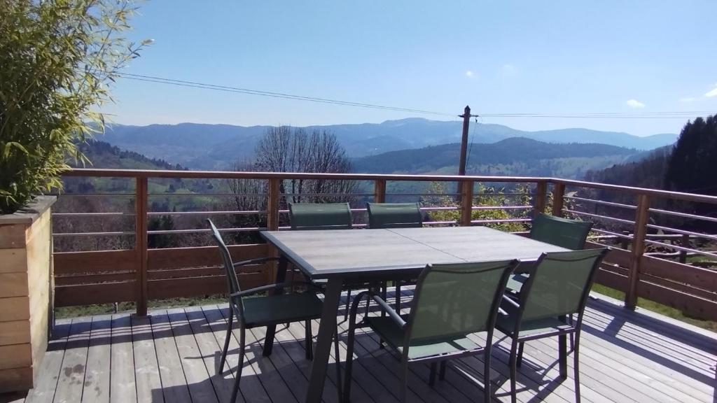 a table and chairs on a deck with a view at Aux balcons de la vallée in Soultzeren
