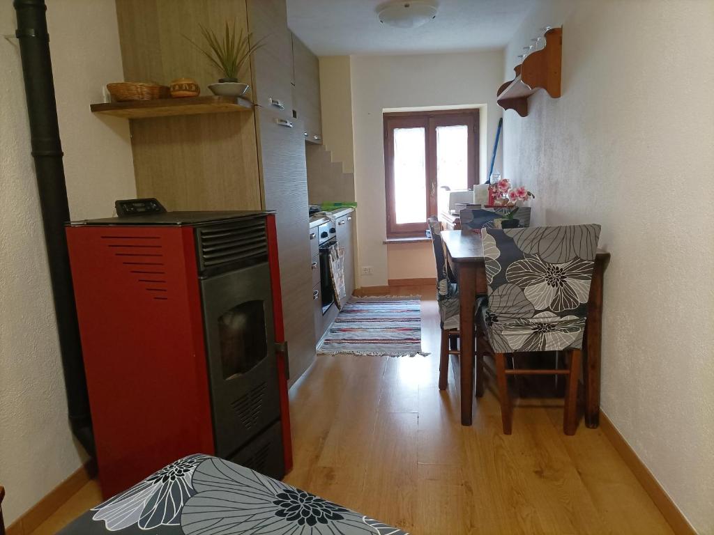 uma cozinha com um fogão vermelho e uma mesa com cadeiras em Casa L' Archetto em La Salle