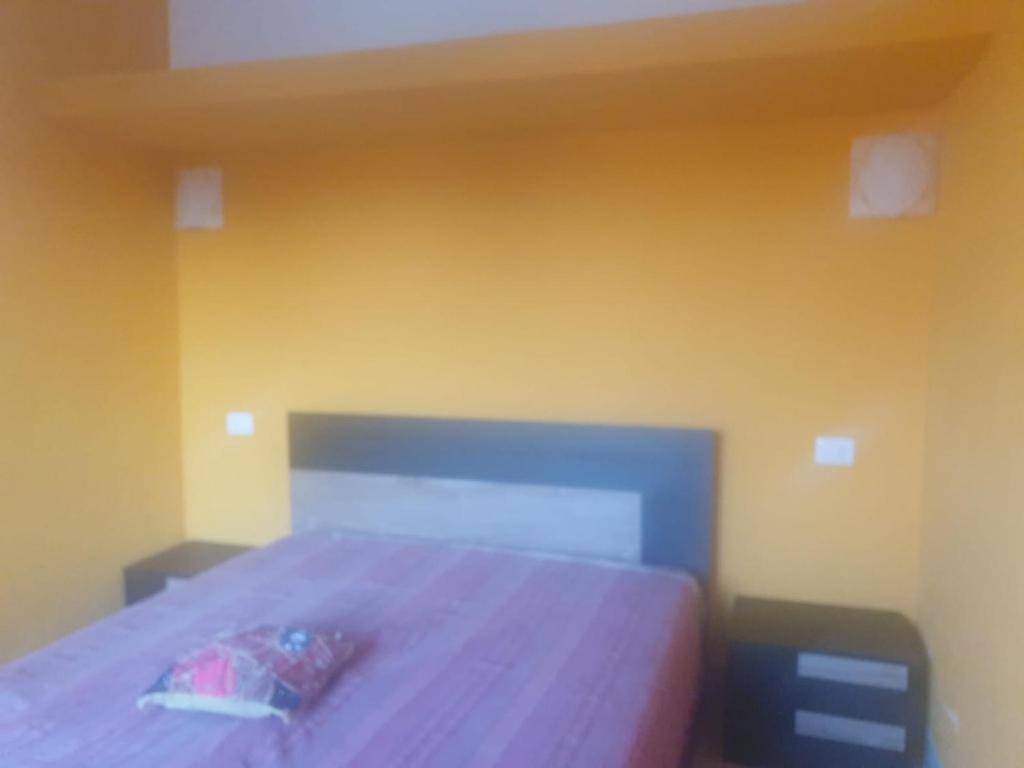 Cama en habitación con pared amarilla en La casetta del bosco, en Marta