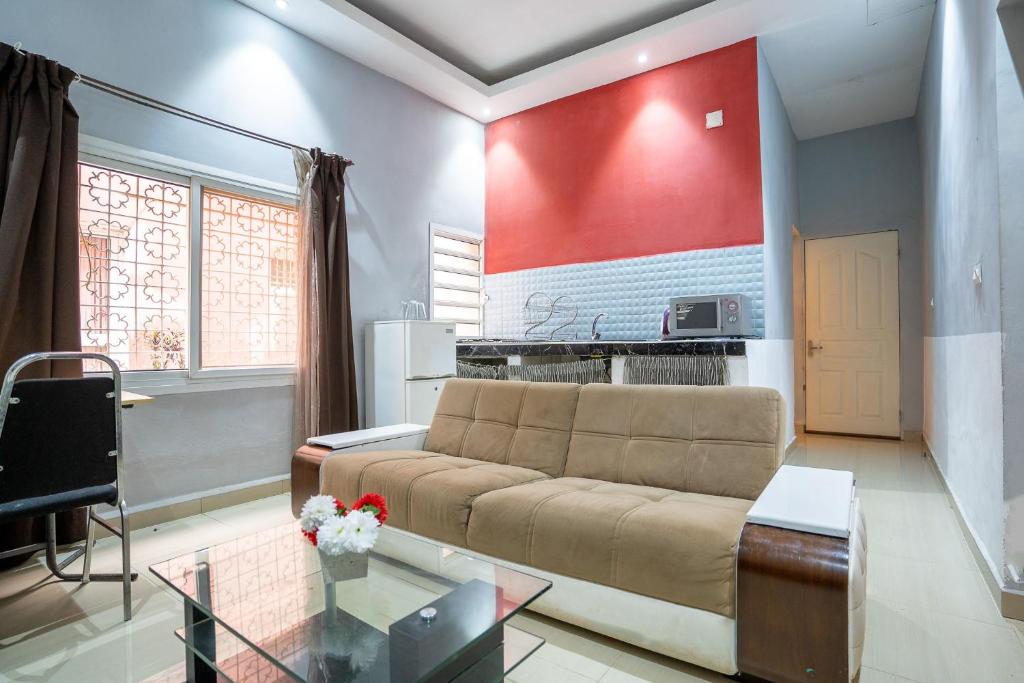 sala de estar con sofá y pared roja en Aparthotel Madeleine, en Antananarivo