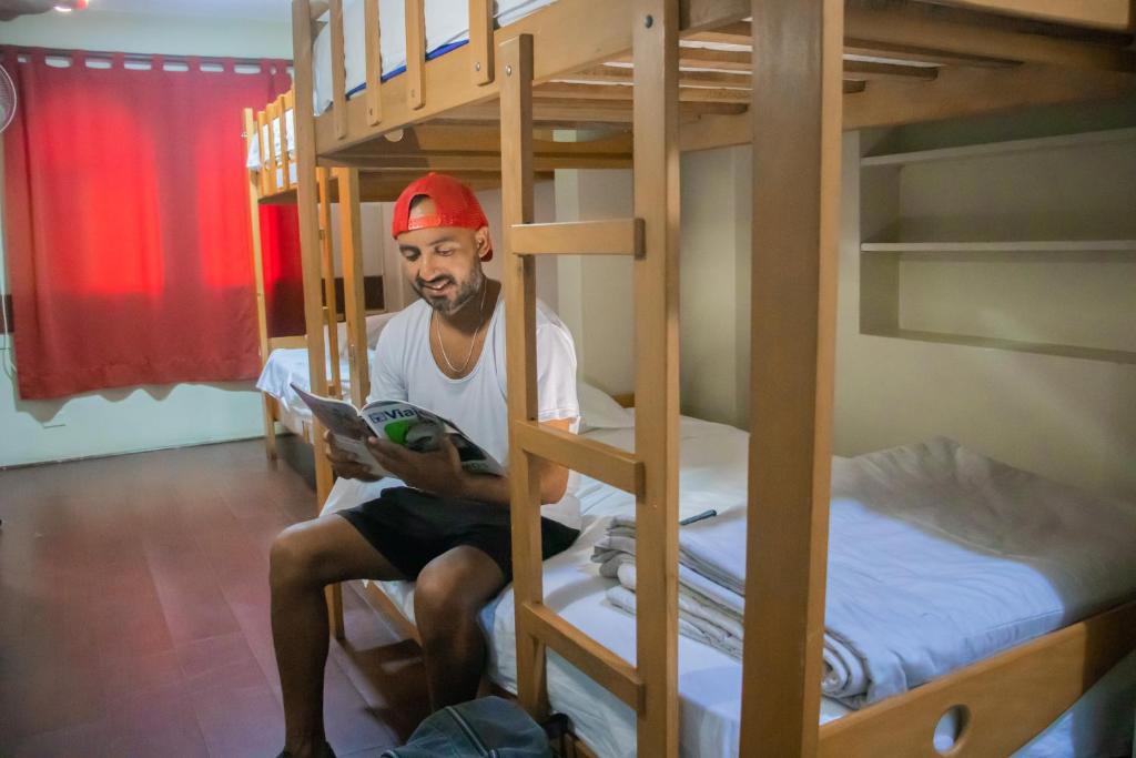 um homem sentado num beliche a ler um livro em Hostel THAY83 Miraflores Lima em Lima