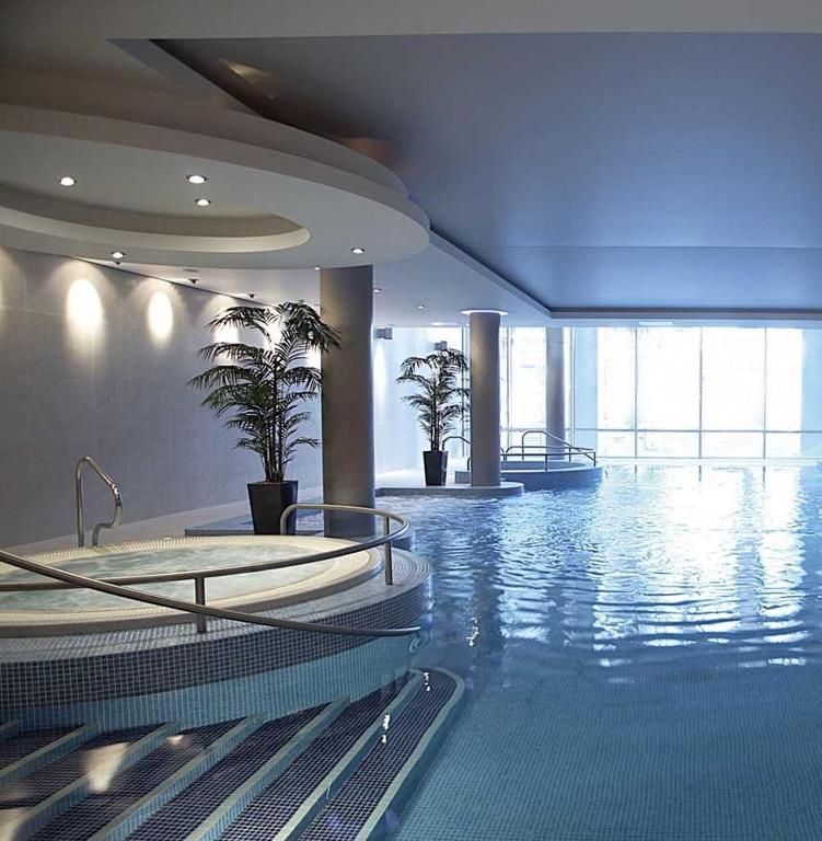 uma grande piscina com duas banheiras de hidromassagem num edifício em The River Lee Hotel a member of The Doyle Collection em Cork
