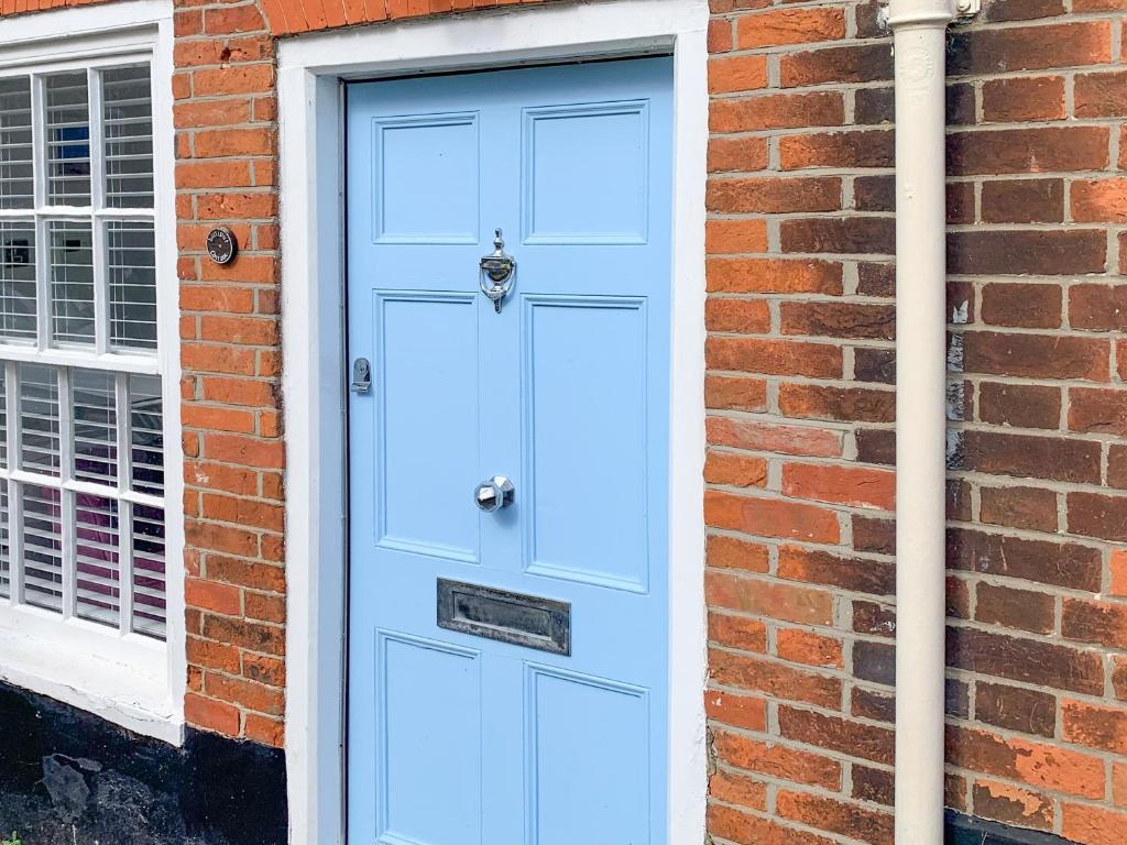 a blue door on the side of a brick building at Lilliput Cottage in Wangford