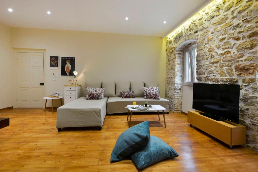a living room with a bed and a stone wall at Beau Maison in Corfu