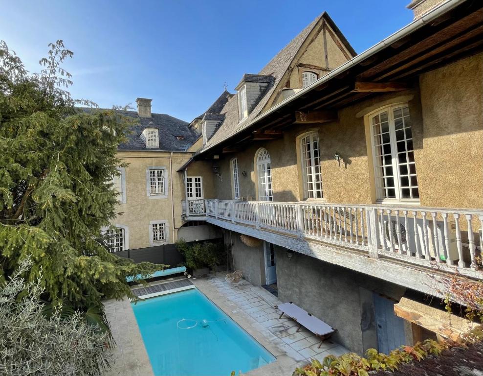 une maison avec une piscine et un balcon dans l'établissement La Maison aux murs anciens et ses chambres, à Tarbes