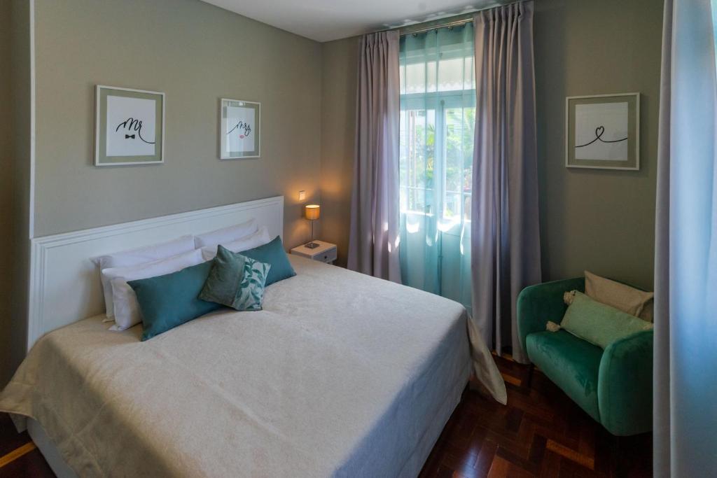een slaapkamer met een bed en een groene stoel bij Blue House in Ponta do Sol