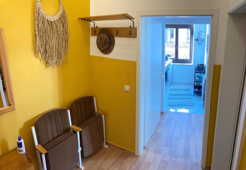 a room with two chairs and a hallway with yellow walls at Sonniges Altstadt Nest in Magdeburg