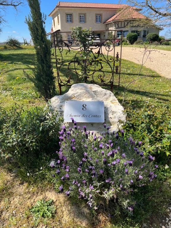 um sinal sentado numa pedra ao lado de algumas flores em Gîte des Contes em Madiran