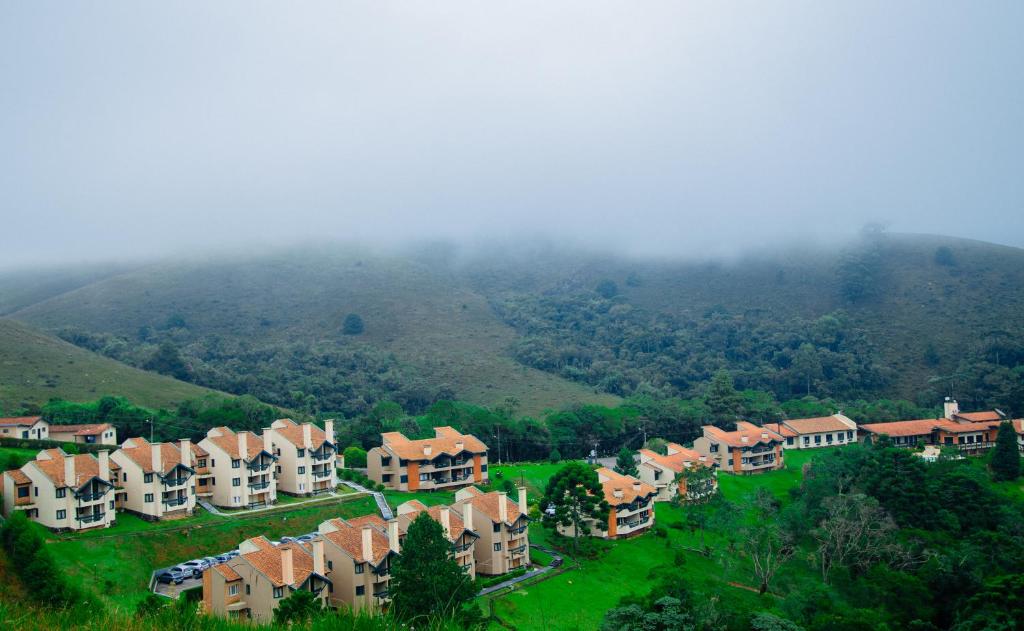 a group of houses on a hill in front of a mountain at Plaza Inn Week Inn in Campos do Jordão
