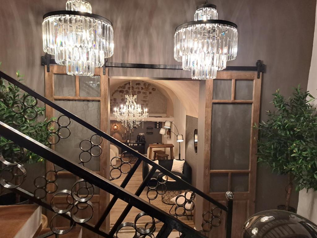 a hallway with chandeliers and a staircase in a house at Hôtel Le Patio de Sophie in Sisteron