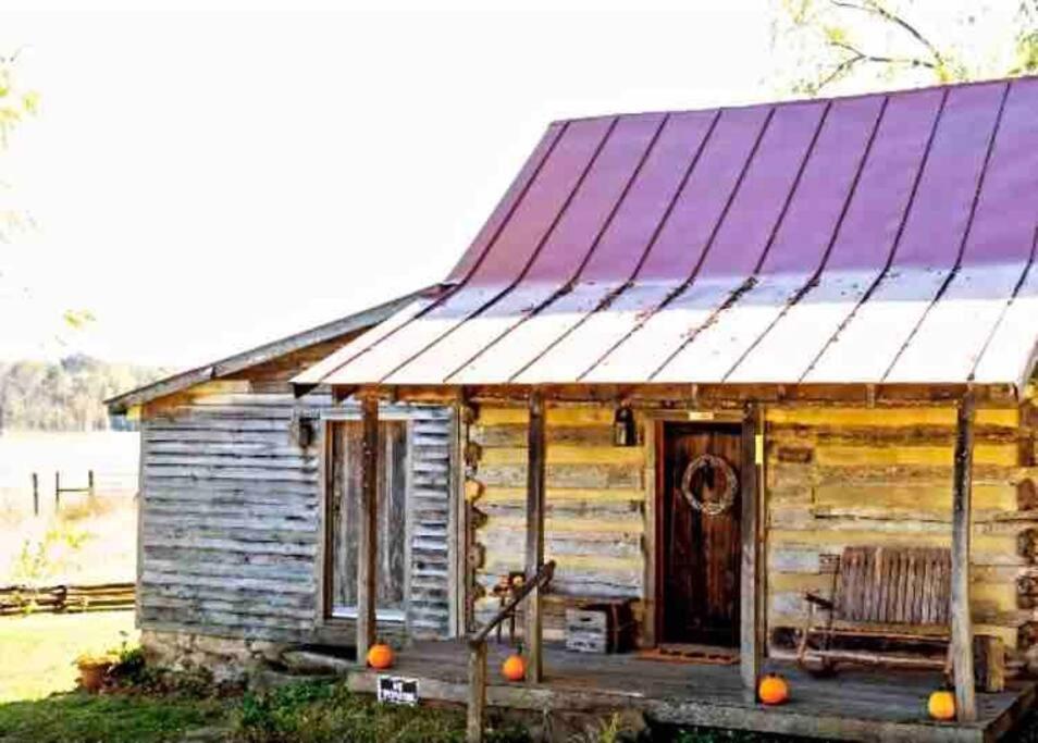 an old wooden house with a porch and a chair at Historic 1850's Cosmic Cabin 