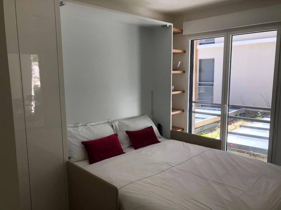 een slaapkamer met een groot bed met 2 rode kussens bij Splendide studio, 10' a pied de Monaco + parking in Beausoleil