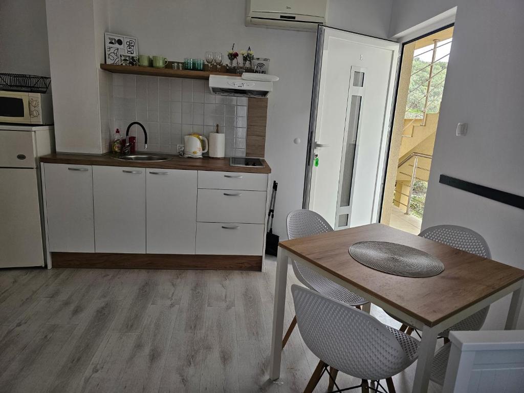 a kitchen with a table and a table and chairs at Apartmani Alma in Podgora