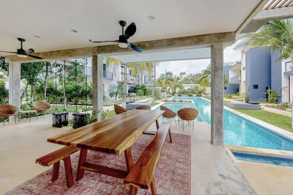 a dining room with a wooden table and a swimming pool at Contemporary poolside Condo, Wi-Fi - Paraiso Kaanal 101 in Tulum