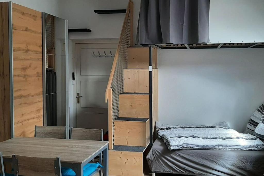 a room with a bunk bed and a table and a staircase at Einzimmerwohnung am Lechweg in Wangle