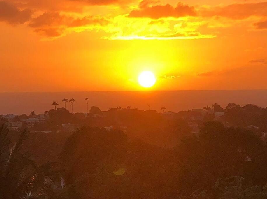 una puesta de sol sobre una ciudad con el sol en el cielo en Chez Tonton David 972 en Fort-de-France