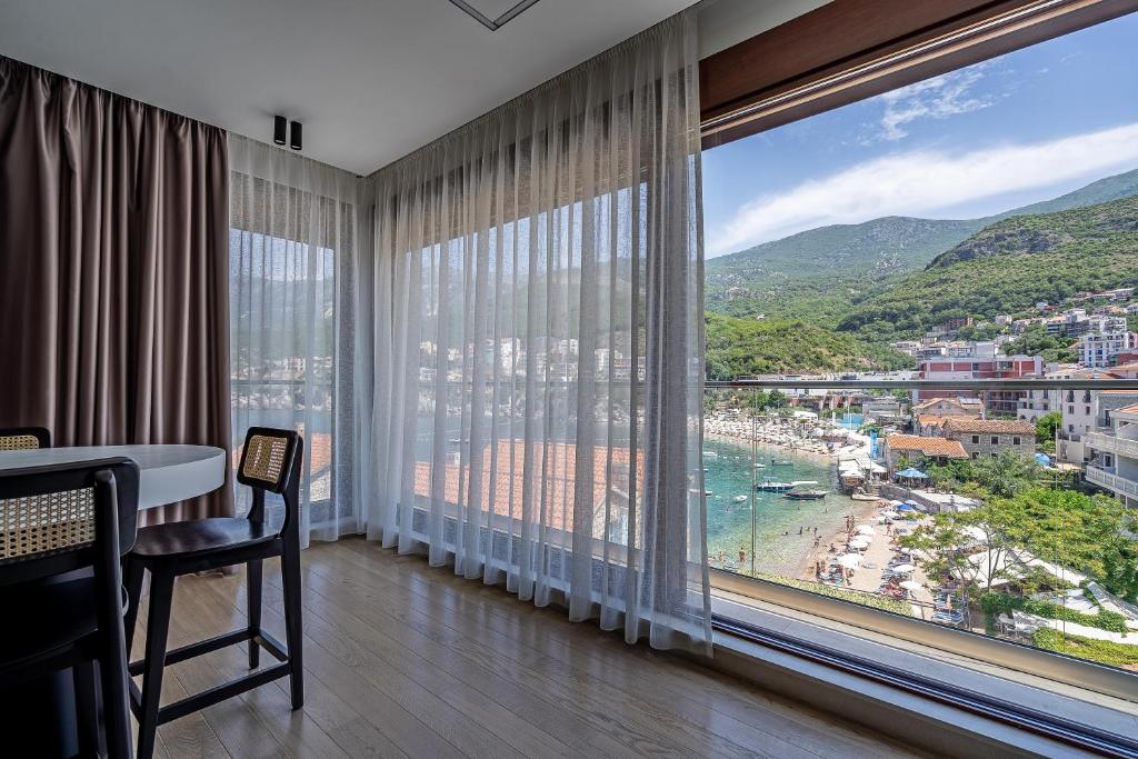 a room with a large window with a view of a beach at Blanche Cliff Apartments in Sveti Stefan