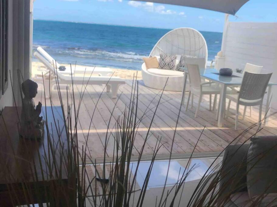 a patio with a table and chairs and the ocean at DREAM ON THE BEACH in Baie Nettle
